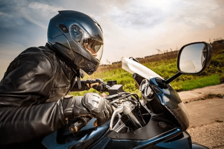 Motard casqué sur sa moto en journée.